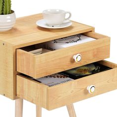 a wooden table with two drawers and a coffee cup on the top one drawer has magazines in it