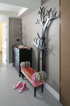 a room with a pink bench and some shoes on the floor next to a tree