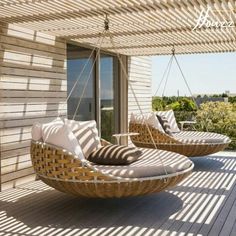 two wicker chairs sitting on top of a wooden deck next to an open window