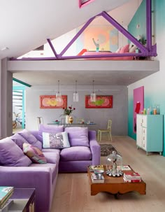 a living room with purple couches and wooden flooring in front of a staircase