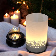 a lit candle sitting on top of a table next to a clock and some candles