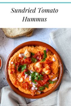 a bowl filled with tomato hummus next to bread