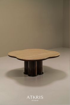 a round wooden table sitting on top of a white floor next to a brown wall