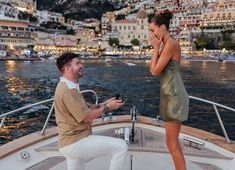 a man and woman sitting on the back of a boat looking at something in their hands