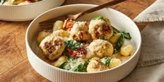 two bowls filled with pasta and vegetables on top of a wooden table next to a fork