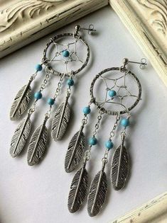 a pair of earrings with feathers and beads