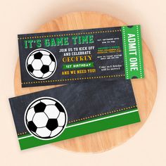 two soccer ticket cards sitting on top of a wooden plate