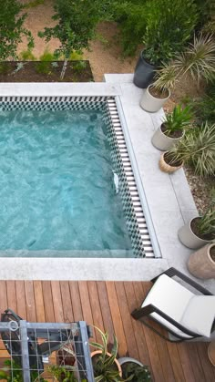 an above ground swimming pool surrounded by plants and potted plants on the decking area