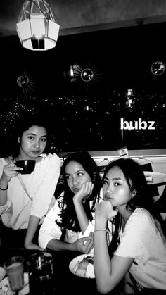 black and white photograph of three women sitting at a table with drinks in front of them