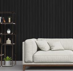 a white couch sitting in front of a black wall next to a shelf filled with books