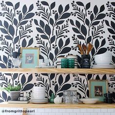 the shelves are decorated with black and white wallpaper, which has leaves on it