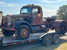 an old truck is on the back of a flatbed trailer