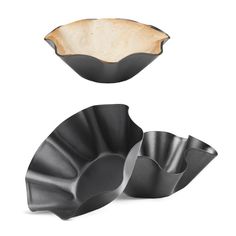 two black bowls sitting next to each other on top of a white surface with one bowl in the middle