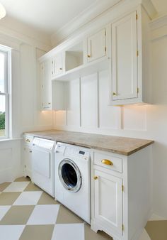 a washer and dryer in a white kitchen with checkered tile flooring