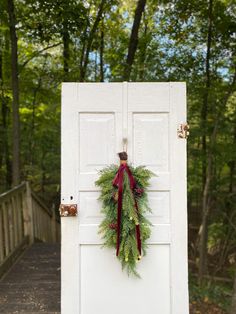 a white door with a wreath on it and a red ribbon hanging from the front