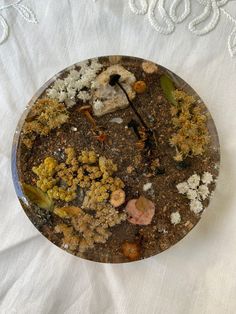 a plate filled with dirt and plants on top of a white table cloth