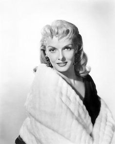 a black and white photo of a woman wearing a fur coat