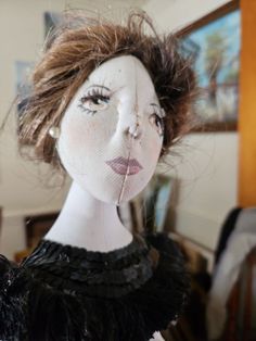 a doll is wearing a black dress and has her hair blown back in the wind