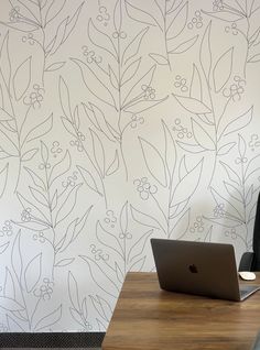 an open laptop computer sitting on top of a wooden desk next to a wallpaper