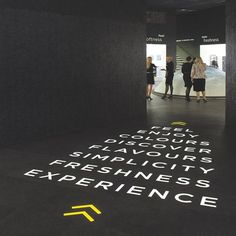 people are standing in an open area with words written on the floor and walls that spell out their experiences