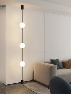 a living room filled with furniture and a white wall next to a lamp that has three lights on it