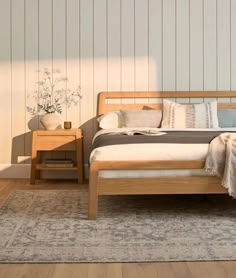 a wooden bed sitting on top of a hard wood floor next to a white wall