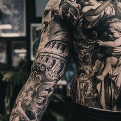 the back of a man's full body with tattoos on his arms and shoulder