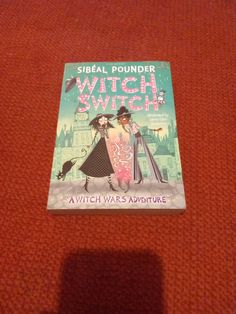 a book with an image of two witches on it sitting on top of a red carpet