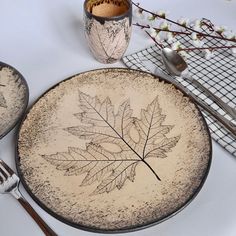 a plate with a leaf drawn on it next to silverware and utensils