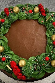 a chocolate cake decorated with green leaves and red berries