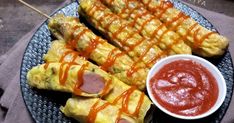 several skewered food items on a plate with ketchup and dipping sauce