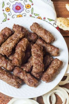 several pieces of meat on a plate with onion rings next to it and breadcrumbs in the background