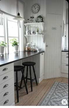 a kitchen with two stools in front of the counter and a clock on the wall