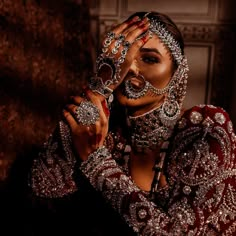 a woman in a red and white dress holding her hands up to her face while wearing jewelry