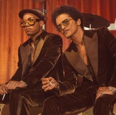 two men sitting next to each other in front of a drum set and wearing sunglasses