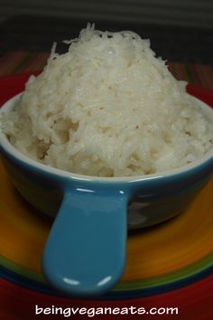 a bowl filled with coconut rice on top of a colorful plate