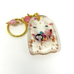 a keychain with an animal in it on a white surface and pink flowers