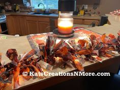 a candle sitting on top of a kitchen counter next to some candy wrapper wrapped around it