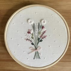 a close up of a embroidery on a wooden surface with flowers in the center and small white balls around it