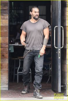 a man with tattoos standing in front of a door