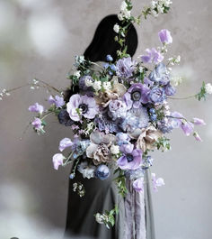 a woman holding a bouquet of flowers in front of her face and wearing a black dress