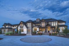 a large white house with lots of windows and lights on it's front porch