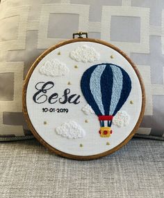 a blue and white hot air balloon with the name essa embroidered on it, sitting next to a pillow