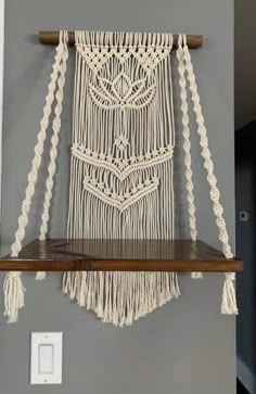 a macrame hanging on the wall above a shelf