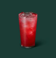 a red drink with ice in it on a green background is seen from the side