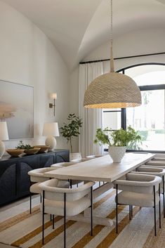 the dining room table is surrounded by white chairs and an oval chandelier above it