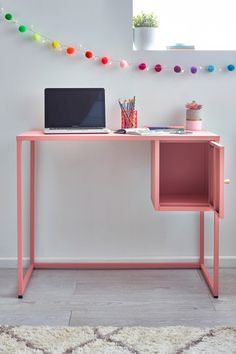 a laptop computer sitting on top of a pink desk next to a white rug and colorful lights