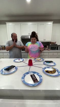 two people standing in front of a table with plates on it, and one person pointing at the plate