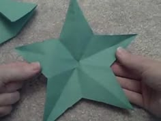 two hands are holding origami stars on the floor