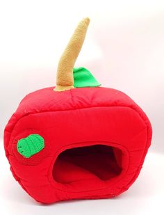 a red apple shaped cat bed with a green leaf sticking out of it's side